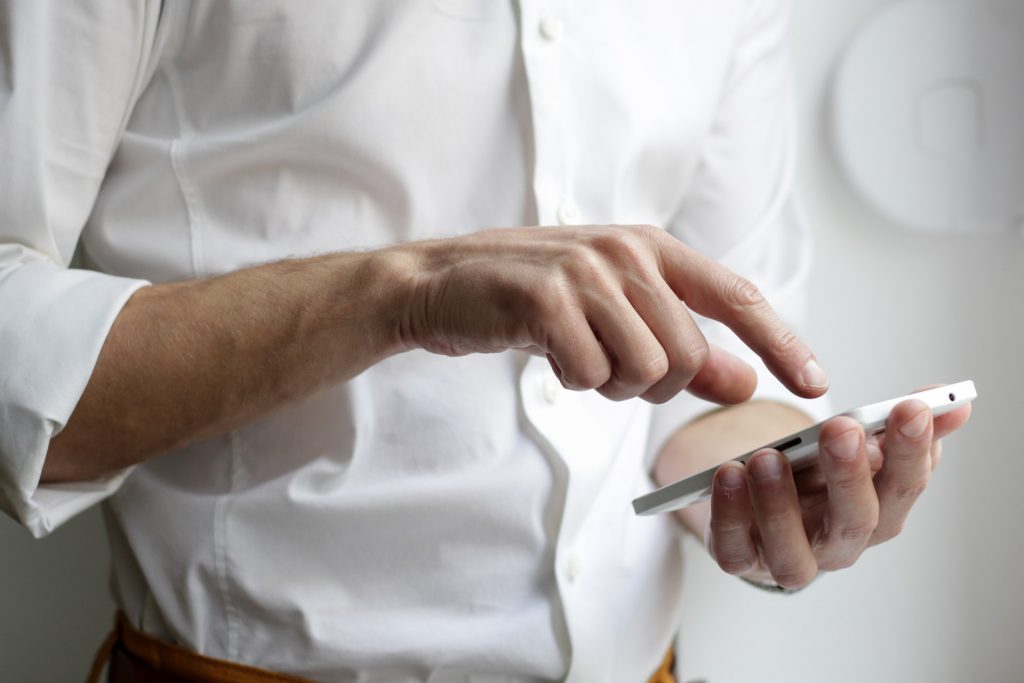 person wearing a white shirt who is dialing on a cellphone